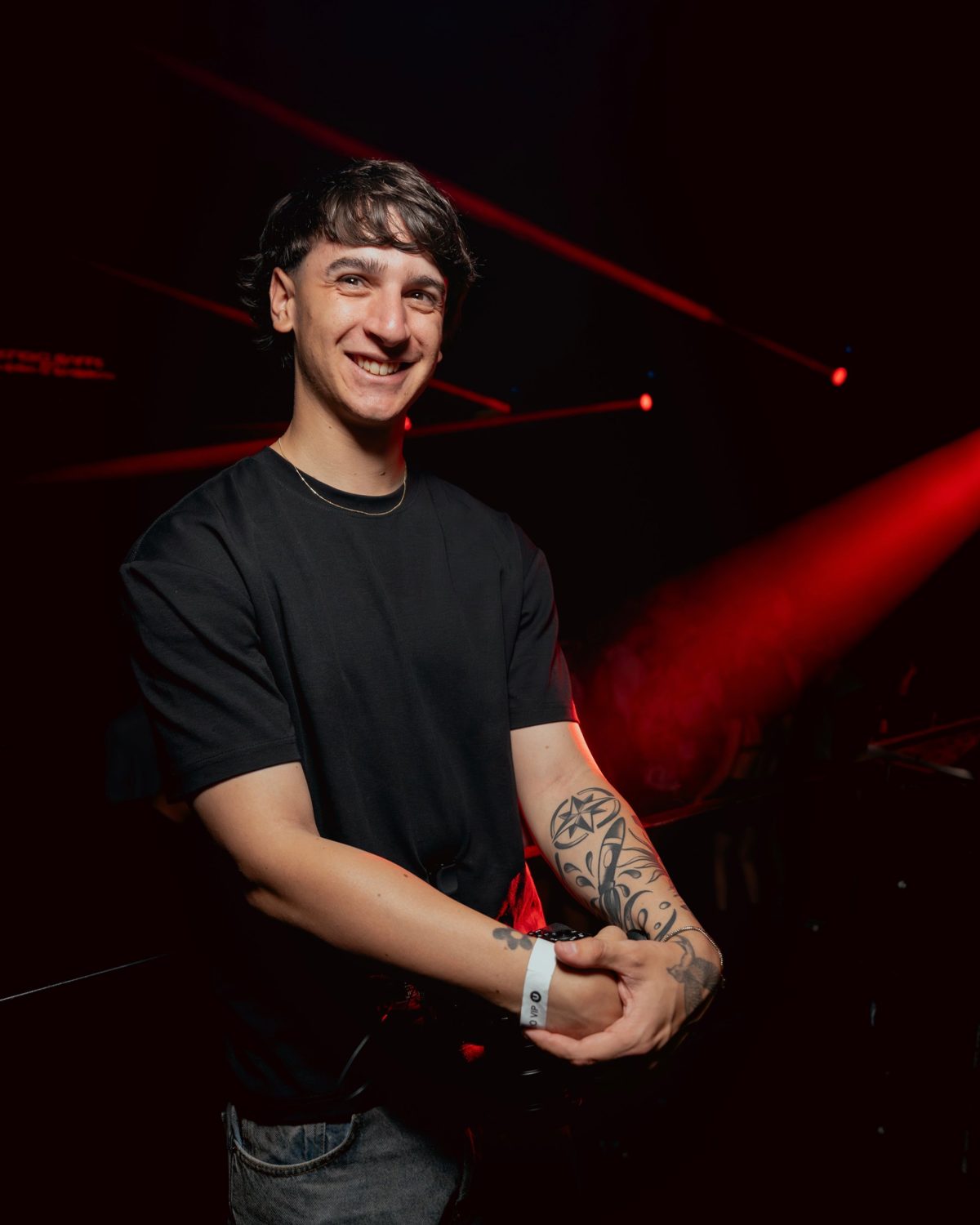 Juan Cruz Cestac sonriendo en un evento con luces rojas